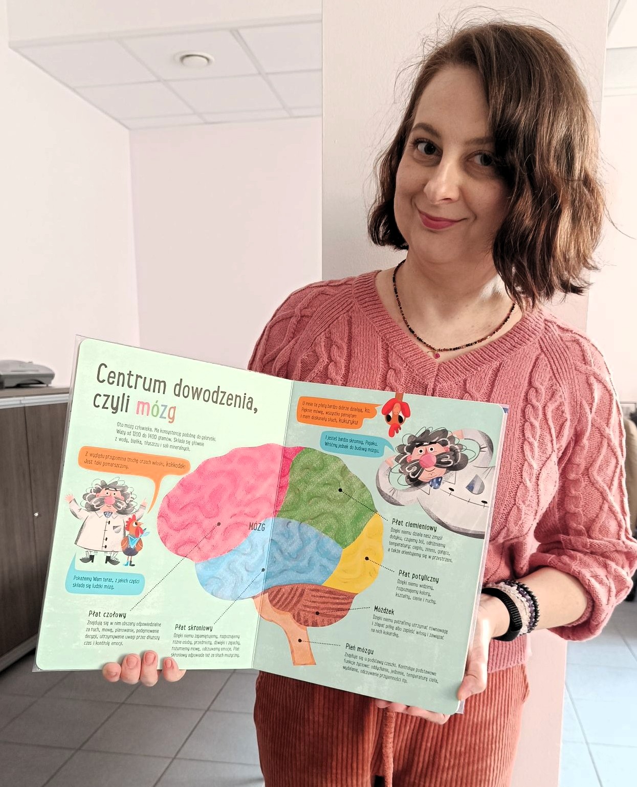Kobieta pokazuje książkę o mózgu i jego działaniu dla młodych czytelników